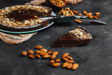 Chocolate cake, chocolate cake, dessert with nuts. a cut piece. Roasted peanuts, almonds and hazelnuts. On dark background. The view from the top. The view from the side. Space for text.