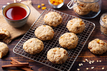 Oat vegan cookies on cooling rack with cup of tea. Wooden background.
