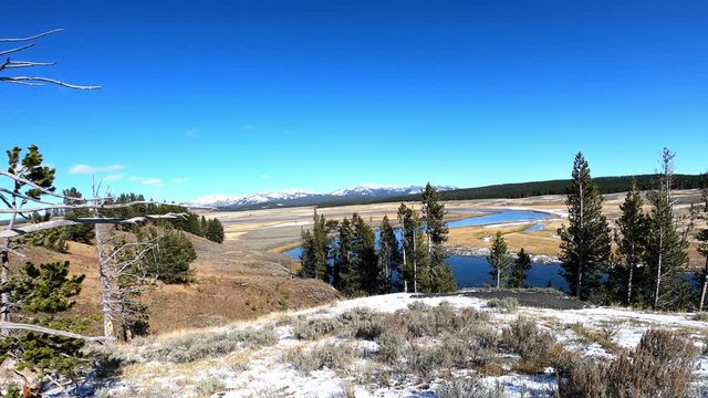 Yellowstone River in the Hayden Valley during fall. Light dusting of snow. Camera panning left to right.