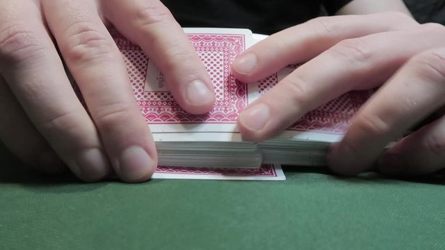 Riffle Shuffle. Male hand shuffling cards on a green cloth. Close-up. Gambling. Games of chance