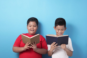 Happy Asian boys reading book together