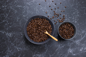 coffee beans in dark bowl cup on isolated dark textured background