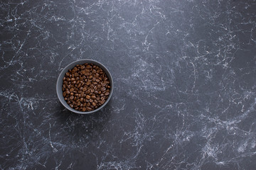 coffee beans in dark bowl cup on isolated dark textured background