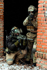 Two men in camouflage cloth green and black uniform with machineguns. Soldiers with muchinegun aims...