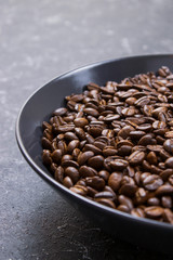 coffee beans in dark bowl cup on isolated dark textured background