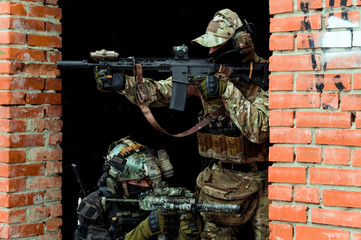Two men in camouflage cloth green and black uniform with machineguns. Soldiers with muchinegun aims...