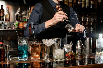 Bartender with special device breaks pieces of ice for cocktails.