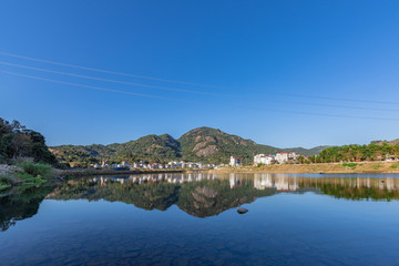 Fototapeta premium Under the blue sky, the rural lake reflects the landscape