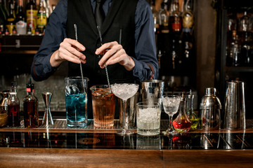 Professional barman pounds cocktails at the bar.