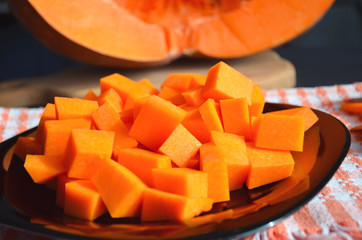 Fresh raw pumpkin on a diced board. Gray-orange background. Vegetarian cuisine.