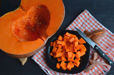 Fresh raw pumpkin on a diced board. Gray-orange background. Vegetarian cuisine.