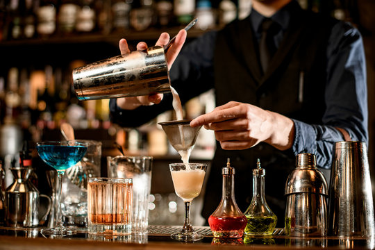 bartender gently pours finished cocktail from the shaker into the glass. - Powered by Adobe
