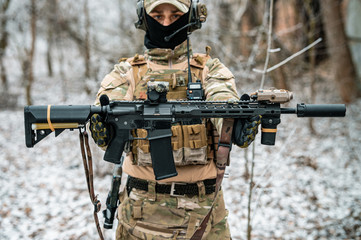 Man in camouflage uniform hold machinegun. Soldier in the winter forest