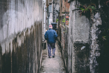 Obraz na płótnie Canvas Old man walking between 2 old walls in a old village