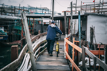 Old man walking with his bicycle on a wooden bridge