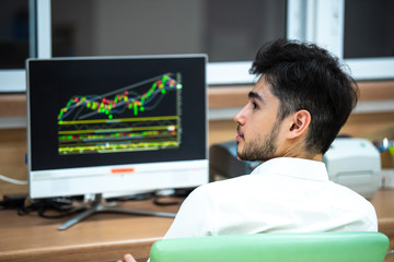 Fototapeta premium A handsome young businessman looking at stock market data from a monitor,select focus.
