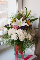 White lilyes, yellow and pink orchids, branch of lilac, chrysanthemums in the spring  tender bouquet on the background with window