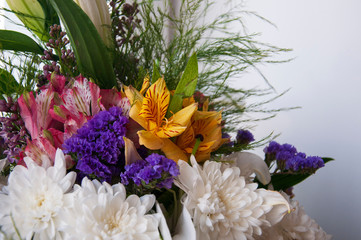 White lilyes, yellow and pink orchids, branch of lilac, chrysanthemums in the spring  tender bouquet on the background with window