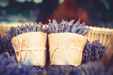 Two bouquets of lavender flowers in a basket wrapped with brown kraft paper and tied with a rope