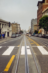 Trolly tracks and pedestrian crosswalk on an urban street with trees