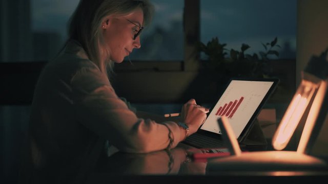Millennial female financial expert working during deadline spending evening for create graphic charts, woman with electronic pen connected to 4g on digital tablet for learning statistic diagrams