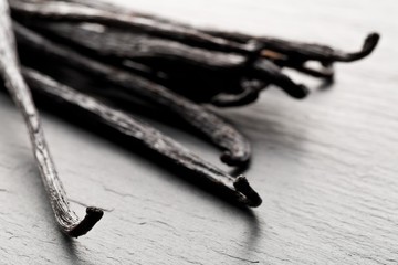 Close up of a bundle of dried bourbon vanilla beans or pods on black stone board