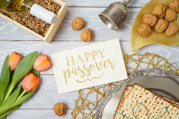 Jewish holiday Passover greeting card with matzo, seder plate, wine and tulip flowers on wooden table. - 328736462