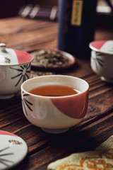 Fototapeta na wymiar Japanese tea into asian porcelain cup on wood table