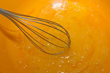 Process of cooking. Whipping egg yolks with a metal whisk.