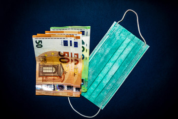 Euro banknotes and medical mask on a dark blue background