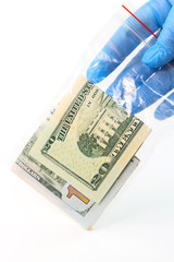 Hand in a rubber glove holds a plastic bag with money