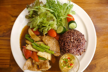 Baked pork berries with vegetable salad topped with sauce placed on the table.