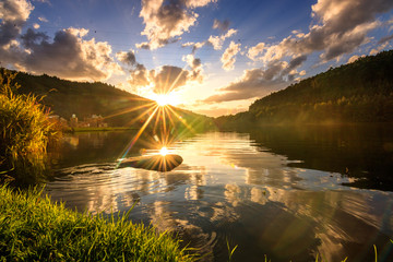 one of the most beautiful sunsets i have ever seen, a calm reservoir in a valley, green and a forest in the area.  the sun sets beautifully in the lake and everything is reflected in the water