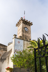 Fototapeta na wymiar Clock tower with the Catholic flag on the territory of the catholic Christian Transfiguration Church located on Mount Tavor near Nazareth in Israel