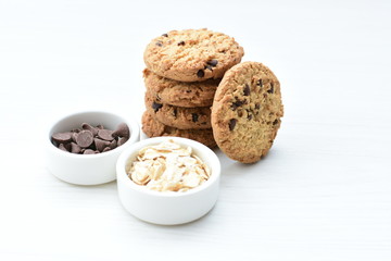 Oatmeal cookies and chocolate chips on light background