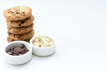 Oatmeal cookies and chocolate chips on light background