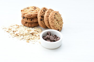 Oatmeal cookies and chocolate chips on light background