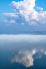 Naklejka na ściany i meble fog above the lake, clouds at sky and its reflection in the water