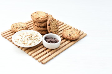 Oatmeal cookies and chocolate chips on light background
