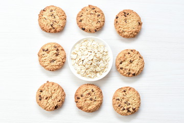 Oatmeal cookies and chocolate chips on light background