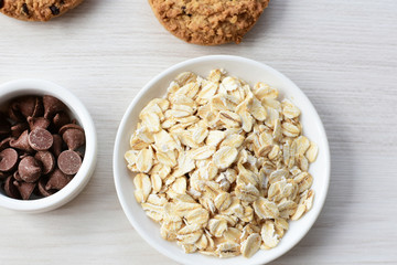 Oatmeal cookies and chocolate chips on light background