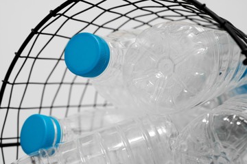 Plastic bottles with blue caps for recycling are in a metal basket. Concept of Recycling plastic and ecology. Plastic waste. Stop nature garbage, ecology environment protection concept.