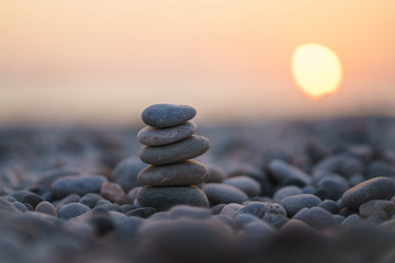 Balanced stone pyramid on pabbles beach with sunset. Zen rock, concept of balance and harmony.