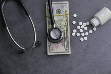 top view of cash, coin and stethoscope on black background