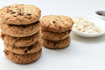 Oatmeal cookies and chocolate chips on light background