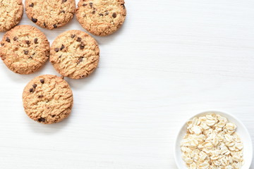 Oatmeal cookies and chocolate chips on light background