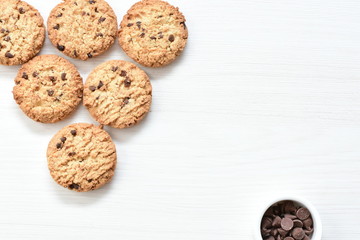 Oatmeal cookies and chocolate chips on light background