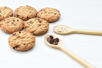 Oatmeal cookies and chocolate chips on light background