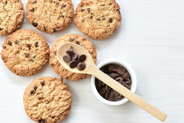 Oatmeal cookies and chocolate chips on light background