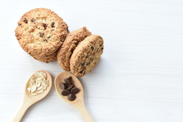 Oatmeal cookies and chocolate chips on light background